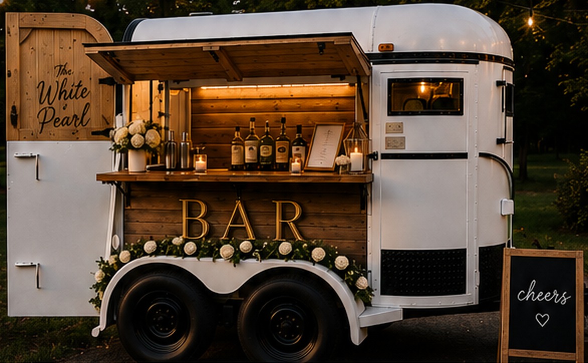 The White Pearl vintage white horse-trailer bar, open and lit at dusk